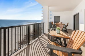 A balcony with a view of the ocean, a table with chairs, and a potted plant. - Palms 915- Premier beachfront condo, 3 bedrooms, sleeps 8, 9th floor (Orange Beach)