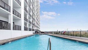 A swimming pool with a metal railing in front, surrounded by a white building with balconies. - Palms 915- Premier beachfront condo, 3 bedrooms, sleeps 8, 9th floor (Orange Beach)