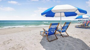 A beach with blue and white beach umbrellas and lounge chairs. - Palms 915- Premier beachfront condo, 3 bedrooms, sleeps 8, 9th floor (Orange Beach)