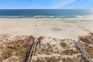 A beach with a clear sky, sandy shore, and a boardwalk leading to the water.