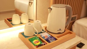 A hotel room with a wooden tray holding a white electric kettle, two white cups, a Lipton tea packet, and a pack of 'EveryDay' cigarettes. - Park Residency Kanchipuram (Kanchipuram)