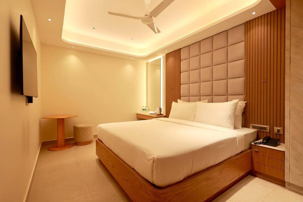 Ein modernes Hotelzimmer mit einem großen Bett, einem Deckenventilator, einem Nachttisch mit Lampe und einem kleinen Rundtisch.