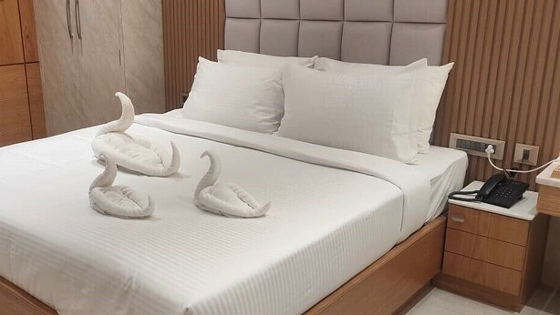 A neatly made bed with white bedding and two swan-shaped pillows. - Park Residency Kanchipuram (Kanchipuram)
