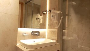 A modern bathroom with a large mirror, a sink, and a glass shower enclosure. - Park Residency Kanchipuram (Kanchipuram)