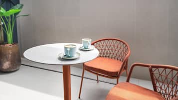 A round table with two chairs, a potted plant, and a window with arches.