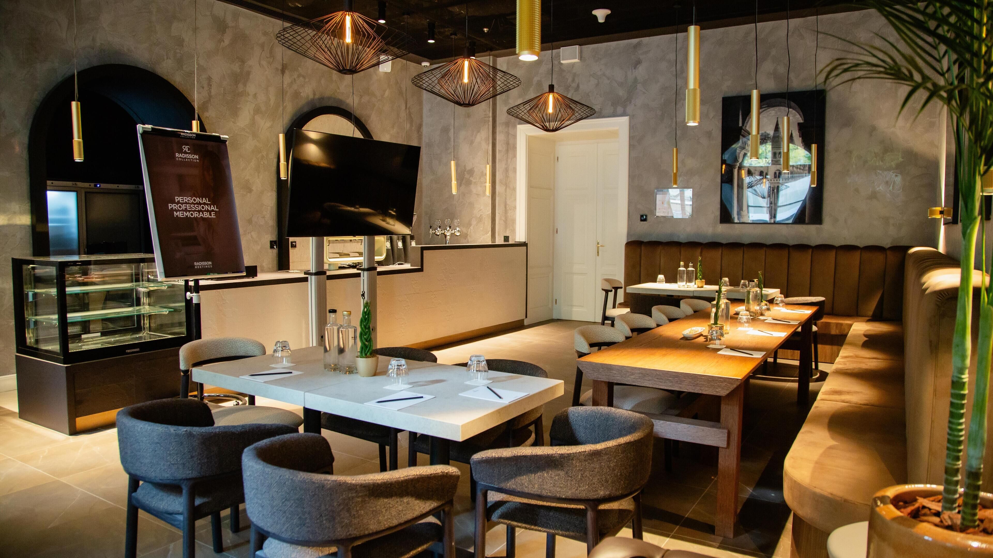 A modern restaurant with a long communal table, individual seating, and contemporary lighting fixtures.