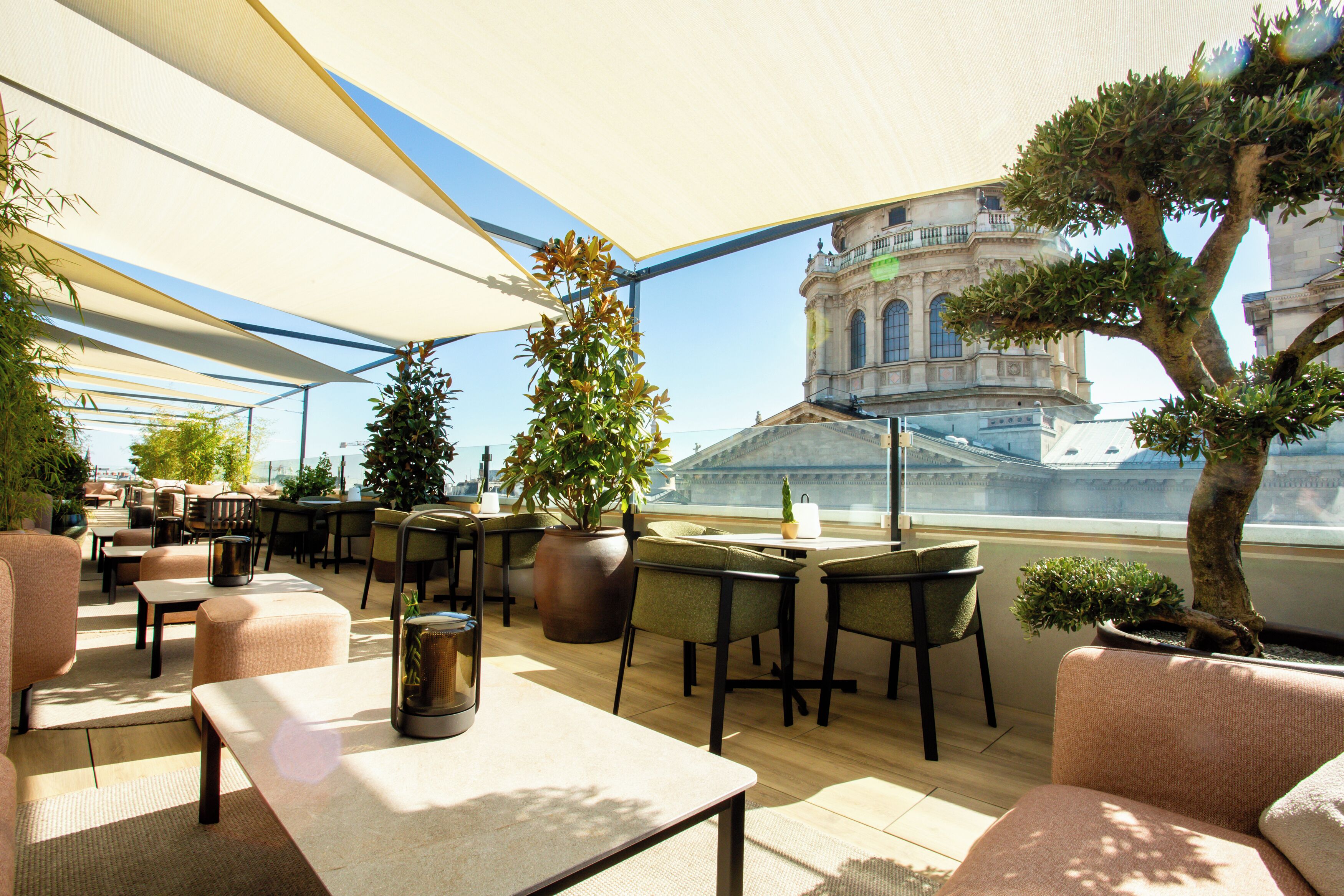 An outdoor seating area with tables and chairs, potted plants, and a view of a historic building.