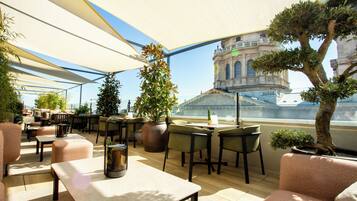 An outdoor seating area with tables and chairs, potted plants, and a view of a historic building.