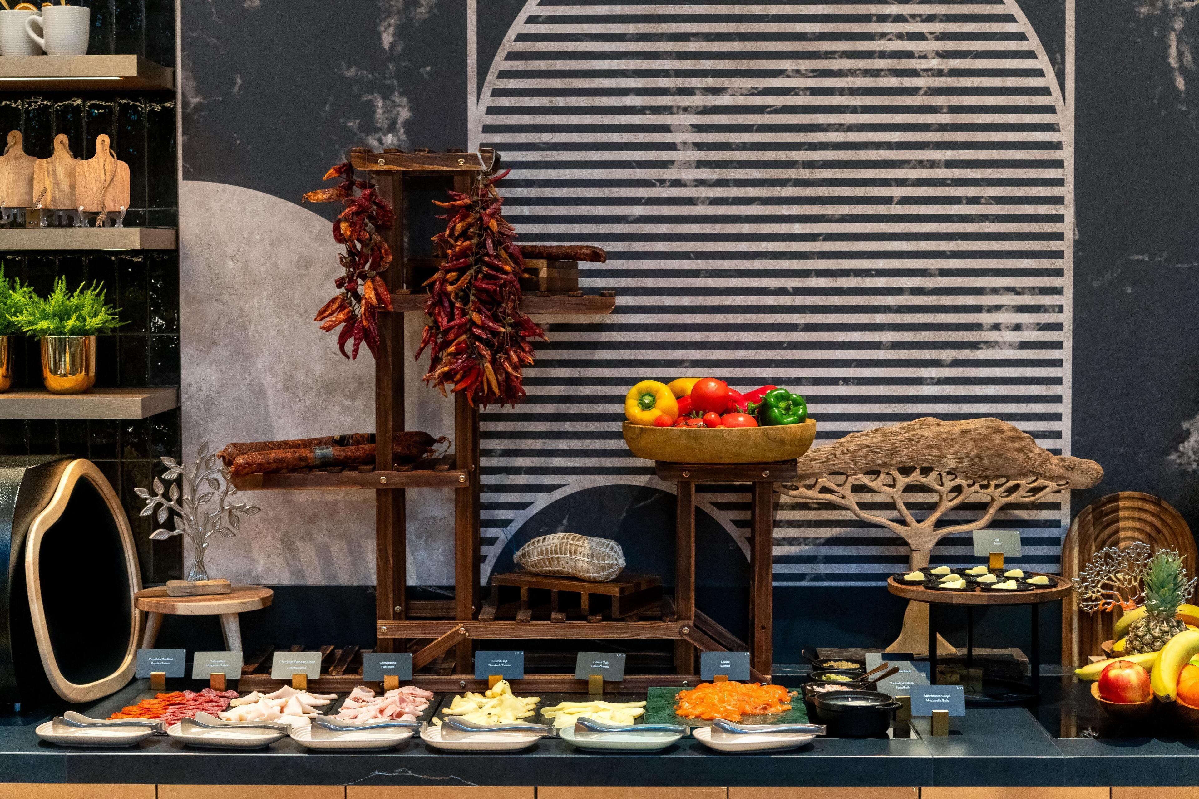 A buffet with various food items and decorative elements like dried chilies, a fruit bowl, and a wooden tree sculpture.