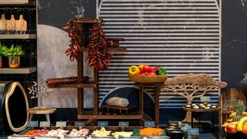 A buffet with various food items and decorative elements like dried chilies, a fruit bowl, and a wooden tree sculpture.