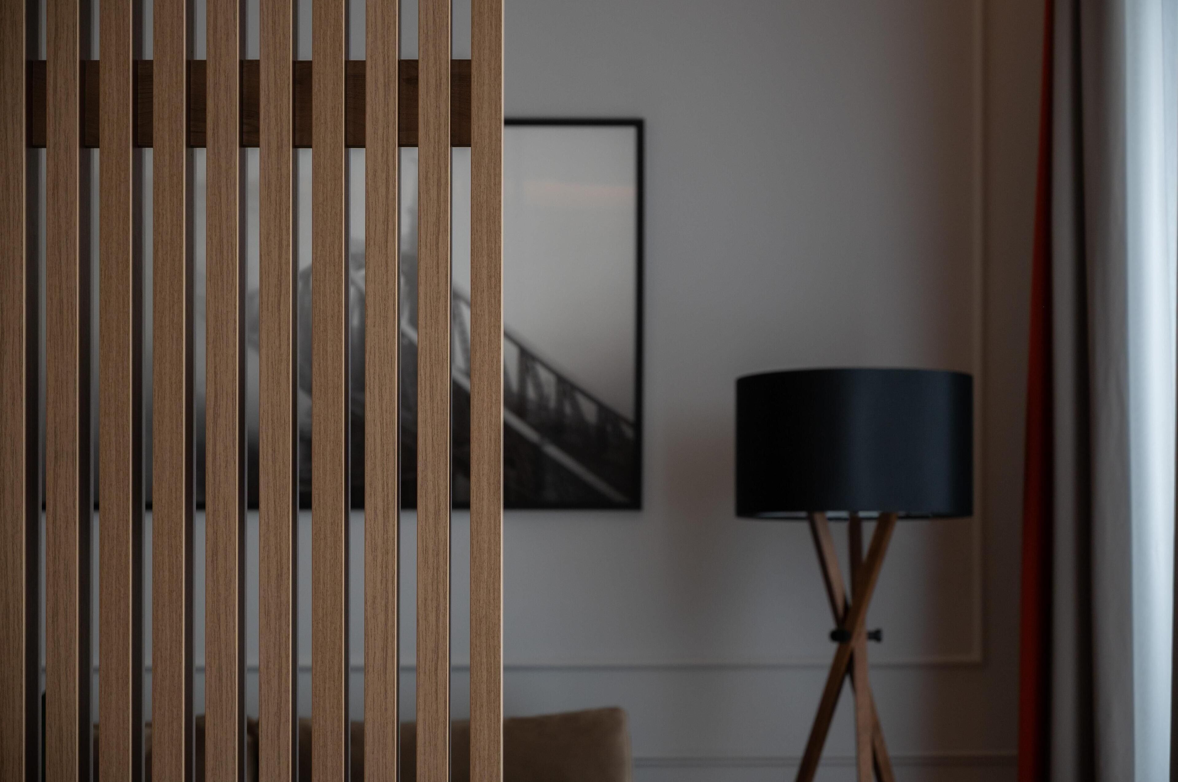 A room with a wooden partition, a framed picture on the wall, and a floor lamp.