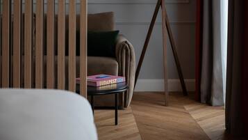 Una habitación con piso de madera, un sofá con un cojín verde y una mesa con un libro titulado 'BUDAPEST GEM'.