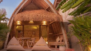 A thatched-roof structure with a pool in front, wooden furniture, and tropical plants. - Villa Palma Gili Meno (Gili Meno)