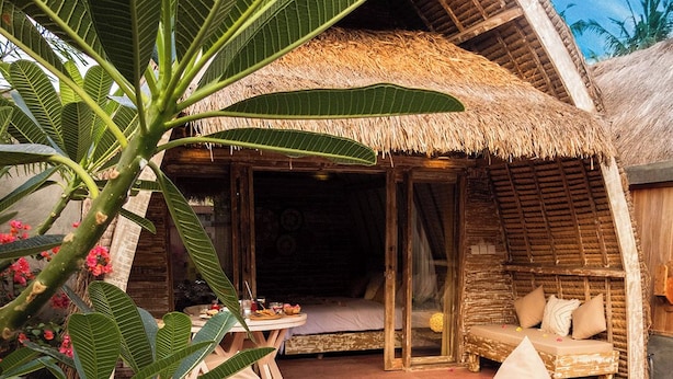 A thatched-roof bungalow with a wooden deck, a pool, and lounge chairs. - Villa Palma Gili Meno (Gili Meno)