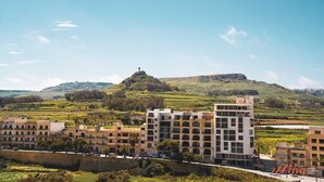 Un ensemble immobilier moderne composé de plusieurs étages, surmonté d’une grande croix au sommet d’une colline.