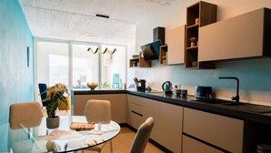 Une cuisine moderne avec une table à manger en verre, des placards intégrés et une vue sur la ville.