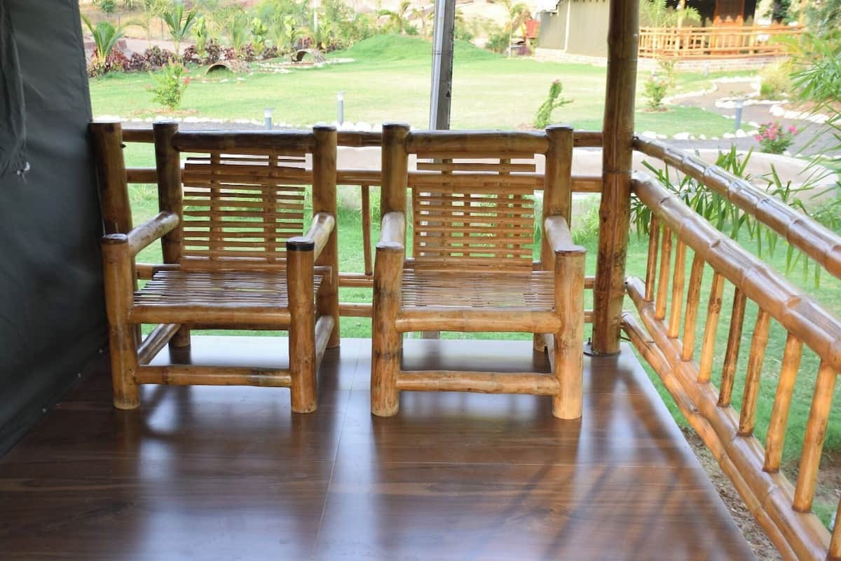 A wooden bench with a metal railing on a balcony overlooking a garden.
