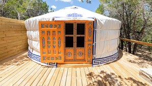 A yurt with a decorative door and a wooden deck. - Secluded, Romantic Yurt w/Hot Tub at The Yurtopian - "Dottie" (Dripping springs)