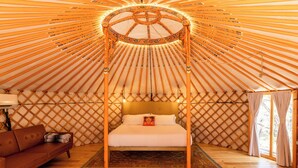 A yurt with a bed, a sofa, and a rug. - Secluded, Romantic Yurt w/Hot Tub at The Yurtopian - "Dottie" (Dripping springs)