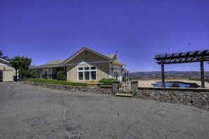 Une maison de plain-pied avec un mur de soutènement en pierre, un patio couvert et une vue sur un paysage montagneux.