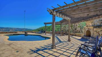 Uma área de piscina com pérgola, espreguiçadeiras e uma parede de pedra.