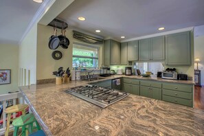 A kitchen with a granite countertop, a built-in stove, and green cabinets. - Napa Vineyard with Stunning Views By Allevo Homes (Napa)
