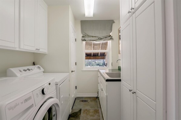 A laundry room with a washing machine, dryer, and a window with a view.