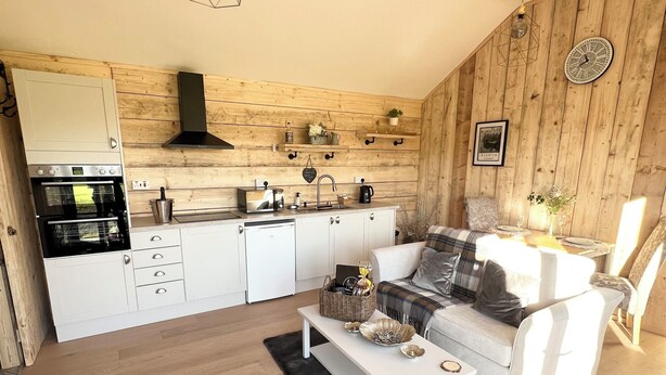 Eine moderne Küche mit weißen Schränken, einem eingebauten Backofen und einer Holzwand.