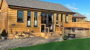 Eine Holzblockhütte mit Terrasse und Whirlpool, mit dem Schild "The Warwick".