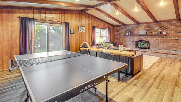 A ping pong table in a room with wooden walls and a brick fireplace. - 4 Mi to Savannah: Home w/ Gazebo & Seasonal Pool! (Garden City)