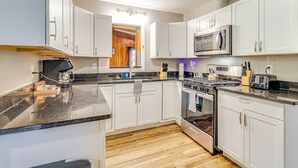 A modern kitchen with white cabinets, a granite countertop, stainless steel appliances, and wooden flooring. - 4 Mi to Savannah: Home w/ Gazebo & Seasonal Pool! (Garden City)