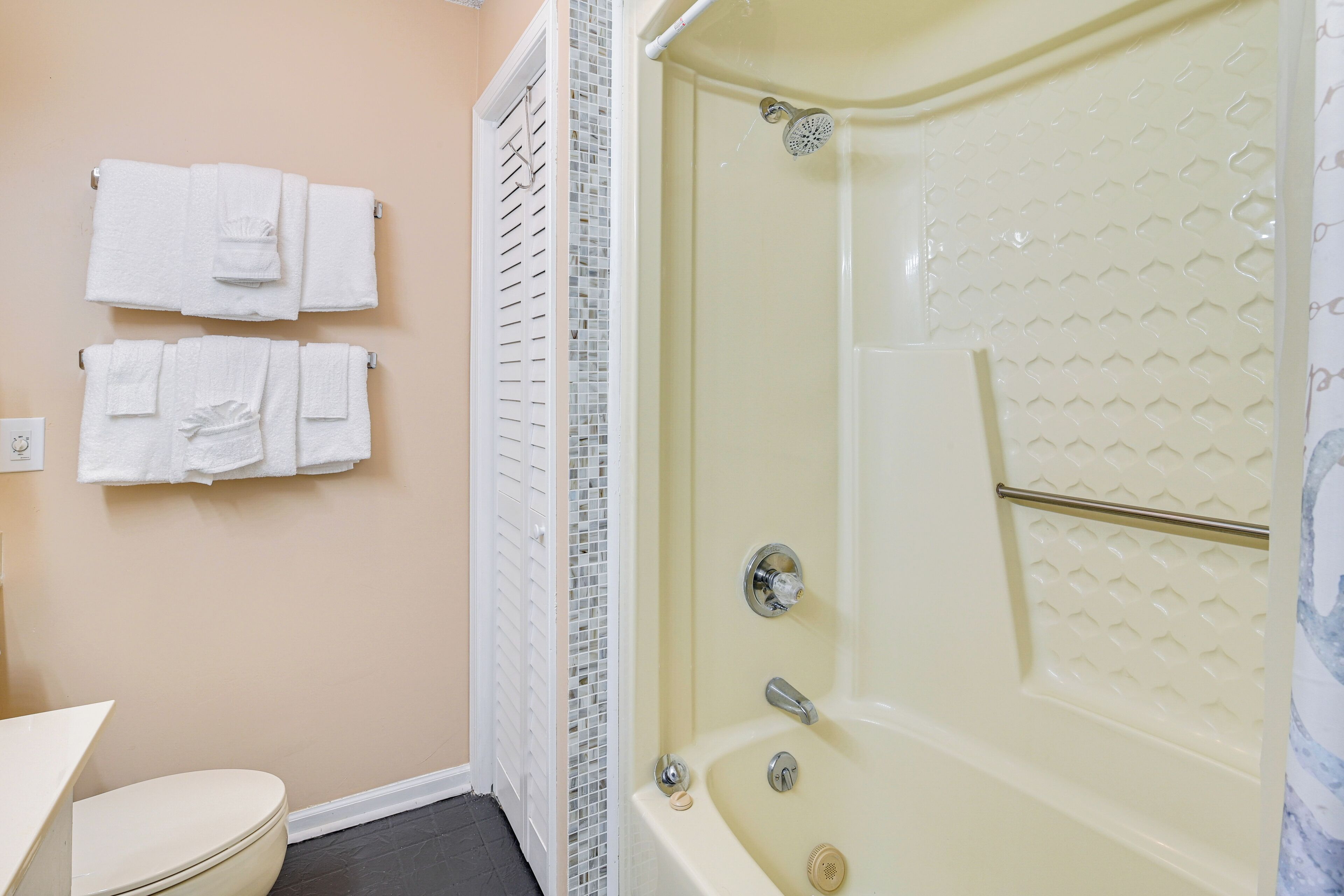 A bathroom with a bathtub, toilet, and towels on the wall.