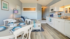 A modern kitchen with white cabinets, a microwave, and a dining area with a table set for four. - Walk to Beach: Top-floor Condo in Murrells Inlet (Murrells Inlet)
