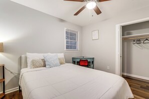 Relax in this serene bedroom with a large bed, ceiling fan, and window with blinds.