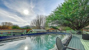 Una piscina con cubierta de madera, rodeada de árboles y una montaña al fondo.