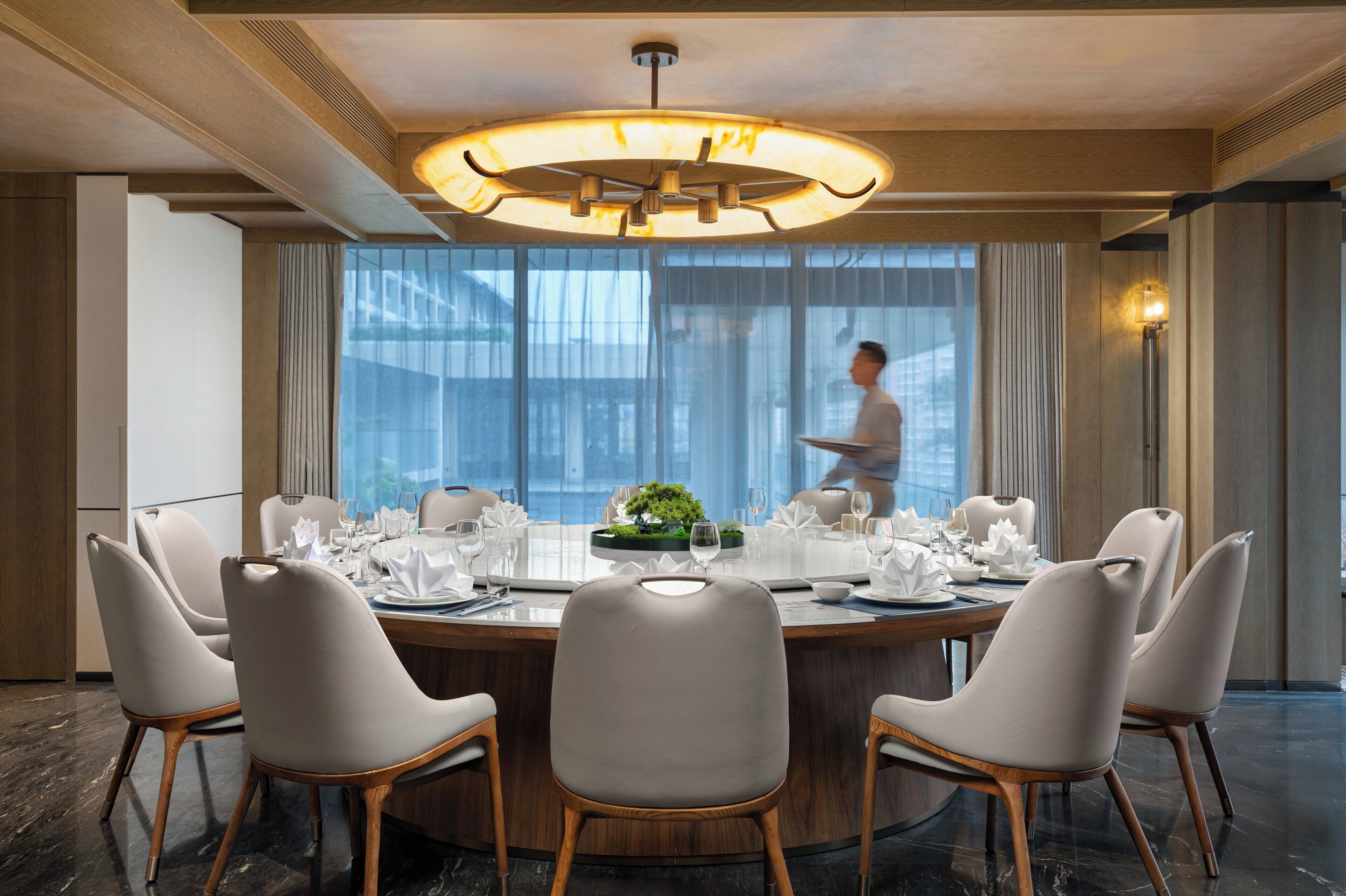 Une salle à manger moderne avec une table ronde dressée pour un repas, entourée de six chaises.