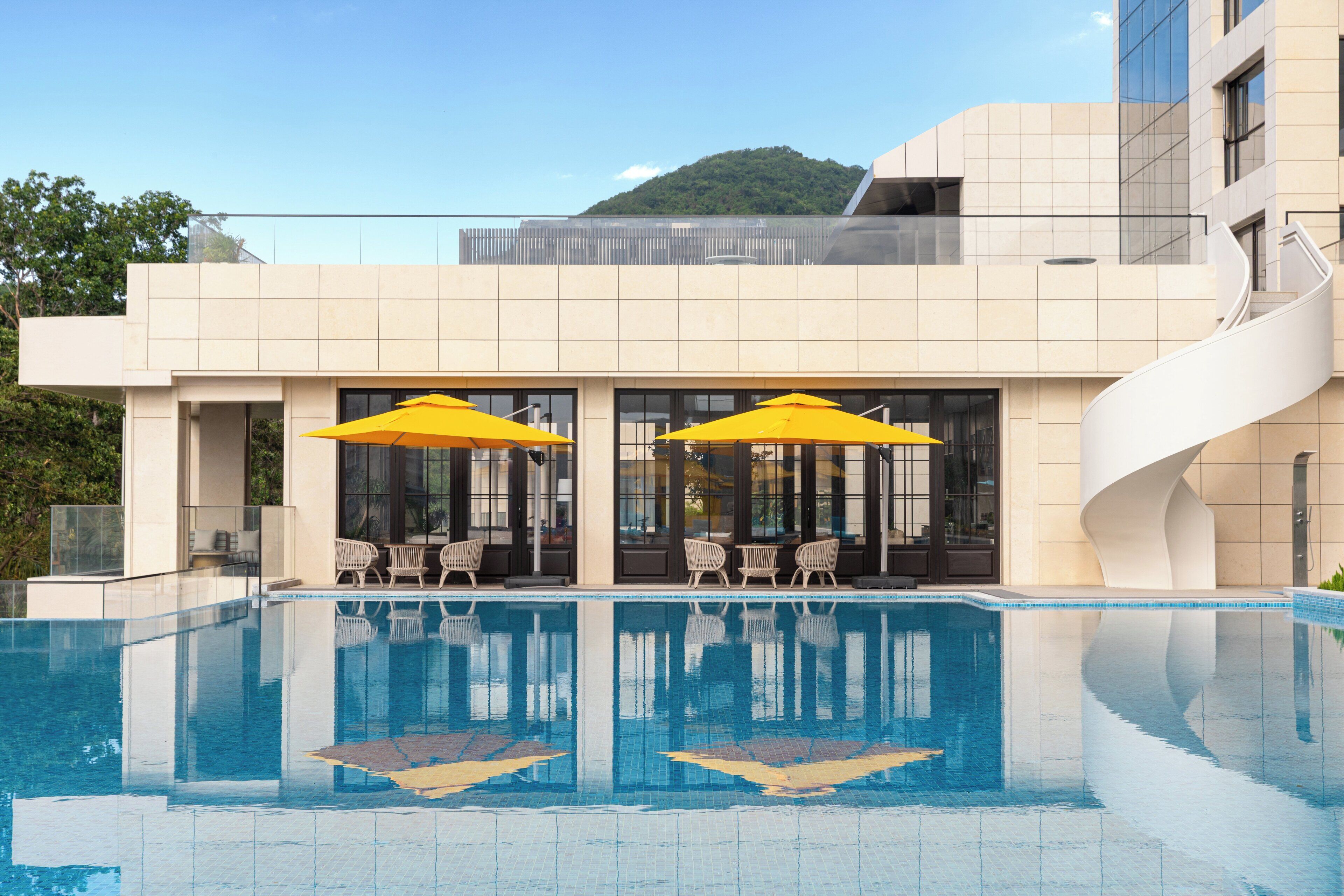 Um hotel moderno com piscina, área de estar externa e vista para uma montanha.