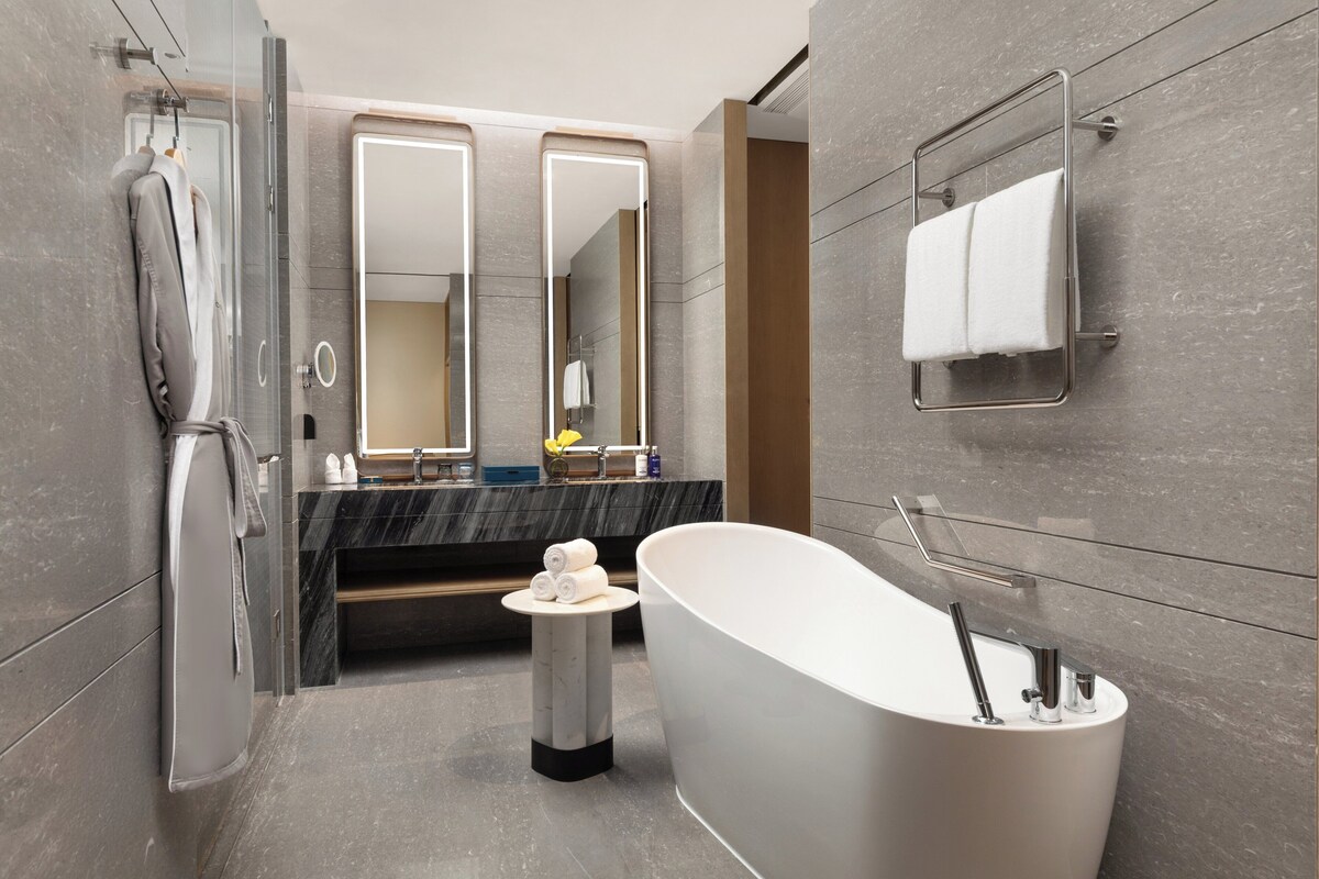 A modern bathroom with a freestanding bathtub, a glass shower enclosure, and a vanity with a mirror.