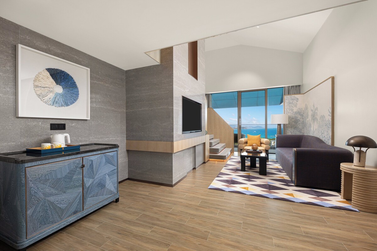 A modern living room with a large window, a flat-screen TV, a sofa, and a coffee table.