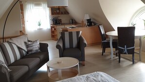 Un loft spacieux avec de hauts plafonds, un coin repas, une cuisine et un coin salon confortable avec un canapé et des fauteuils.