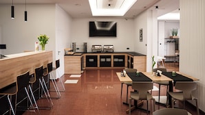 A modern kitchen with a central island, bar seating, and a dining area with chairs and tables. - Hotel Reśliński (Grodzisk Wielkopolski)