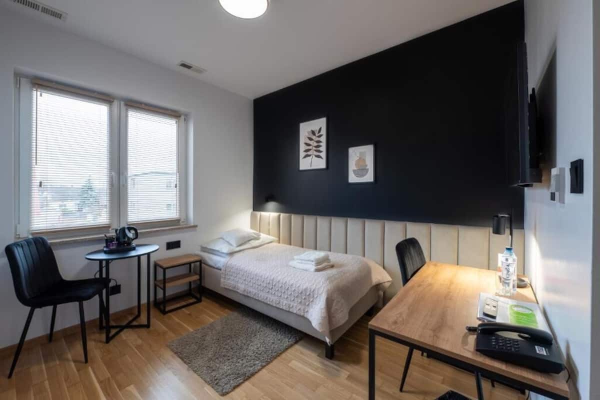 Una habitación de hotel con cama, mesita de noche, silla, escritorio y televisor.