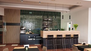 A modern restaurant with a bar area, high chairs, and a tiled backsplash. - Hotel Reśliński (Grodzisk Wielkopolski)