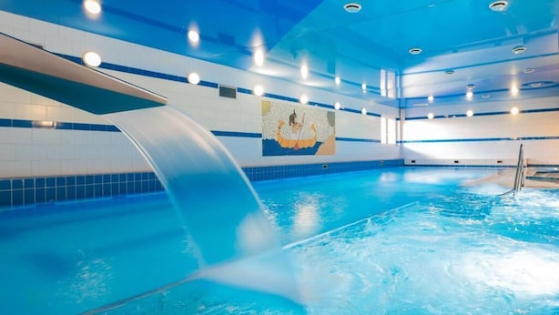 An indoor swimming pool with a clear water surface, a diving board, and a mural on the wall. - Hotel Reśliński (Grodzisk Wielkopolski)