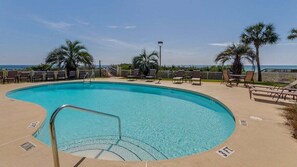 A pool with a 3 ft depth marker, surrounded by lounge chairs and palm trees, with a clear view of the ocean.