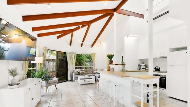 A modern kitchen with white cabinetry, a wooden ceiling, and a large window. - Green Cottage in Trinity Beach (Trinity Beach)