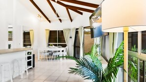 A spacious kitchen with a dining area, white furniture, and large windows. - Green Cottage in Trinity Beach (Trinity Beach)
