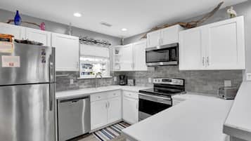 A modern kitchen with white cabinets, stainless steel appliances, a microwave, oven, and a toaster.