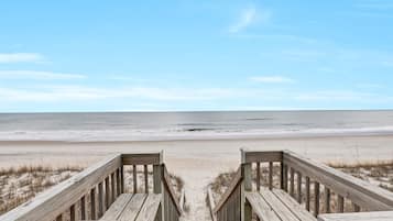 A wooden boardwalk leading to a beach with a clear view of the ocean.