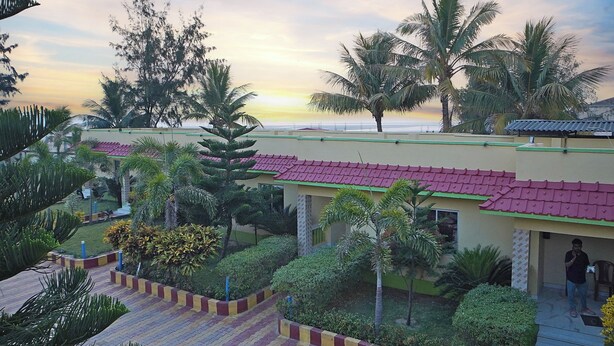 A resort with multiple buildings, palm trees, and a view of the ocean at sunset. - Marino Beach Resorts (Kanthi)
